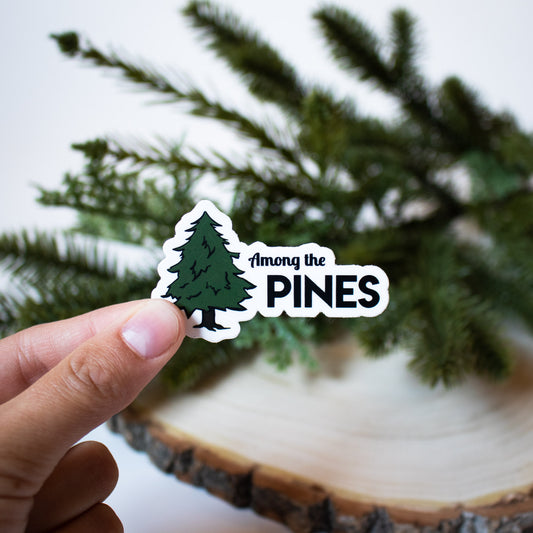 Among the pines in black text on white background. Pine tree illustration in green and brown.